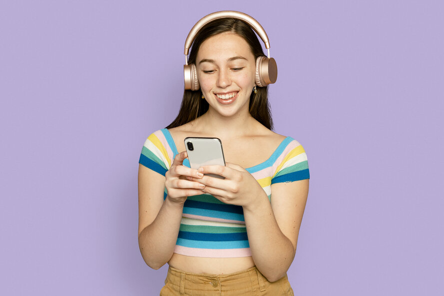 Jeune femme souriante tenant un appareil numérique avec des écouteurs.
